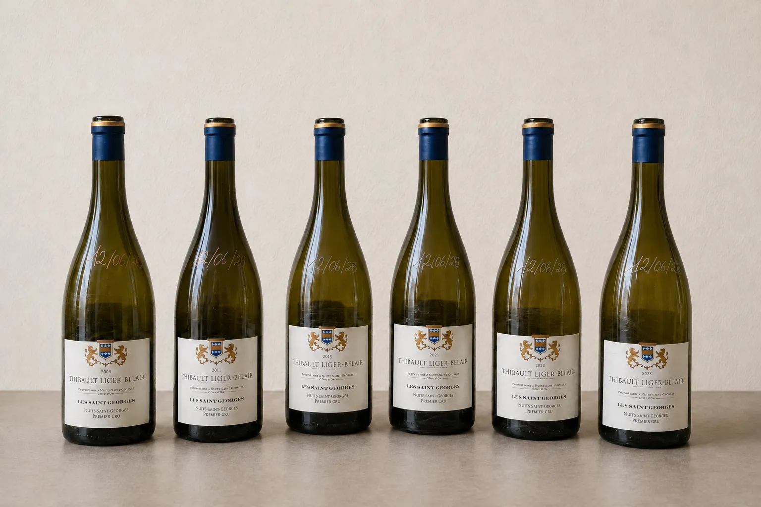 Sei bottiglie di Thibault Liger-Belair Les Saint-Georges allineate, annate dal 2005 al 2023, su parete chiara.